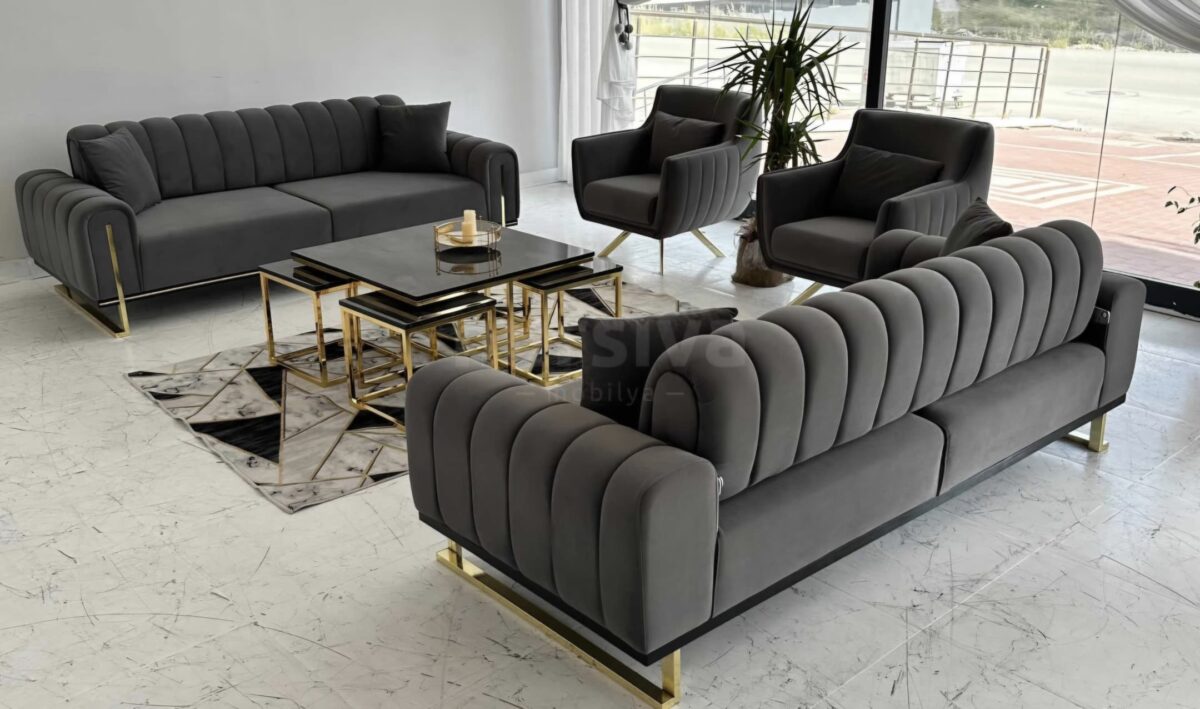Elevate your modern living room with the luxurious Glory Series IX Premium Fabric 7-Seater Sofa Set in elegant gray. This contemporary space features stylish gold-accented coffee tables, a lush indoor plant positioned beside expansive windows draped with white curtains, and stunning marble flooring that adds a touch of sophistication. Perfect for those seeking upscale comfort and timeless design in their home decor.